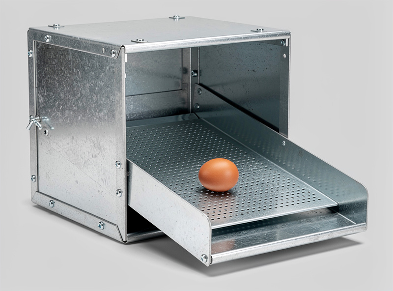 Galvanized metal roll-away nesting box system with angled floor showing a brown egg rolling toward the collection tray