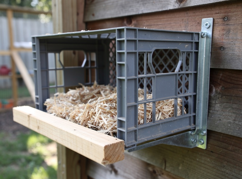 Milk crate converted into a chicken nesting box mounted on a coop wall with L-bracket
