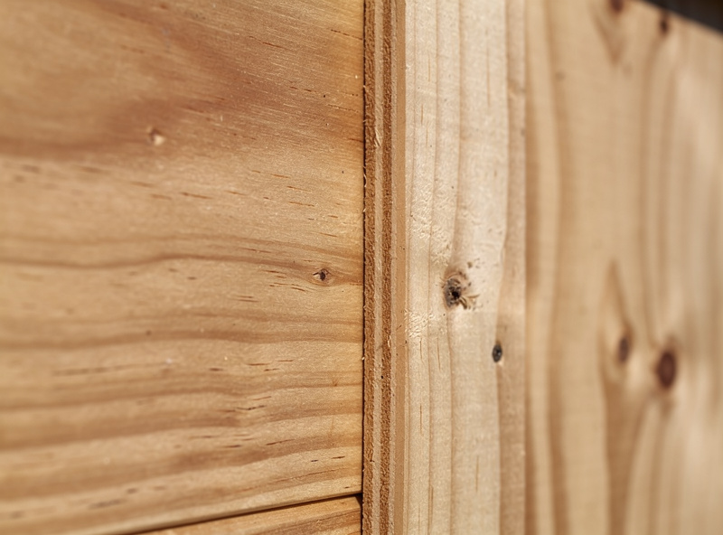 Close-up of an exterior-grade plywood wall of a chicken coop showing the protective stain finish and clean seams