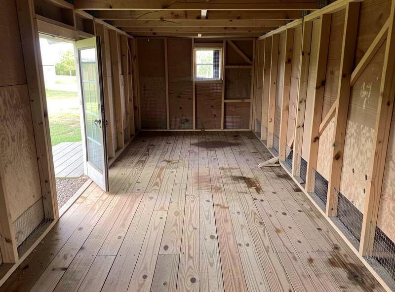 Chicken coop fully stripped out during a seasonal deep clean with bare scrubbed floor drying before fresh bedding