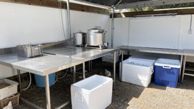 A clean organized outdoor poultry processing setup with stainless steel tables and coolers
