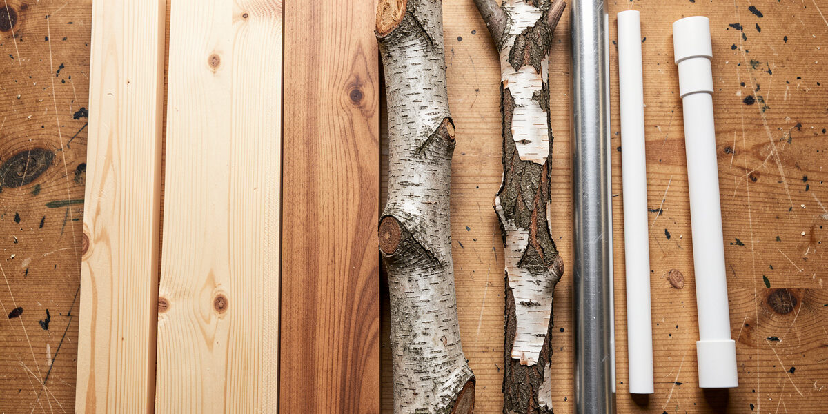 Workbench lineup of roost materials: pine 2x4, hardwood, natural branch, and rejected metal and PVC pipe
