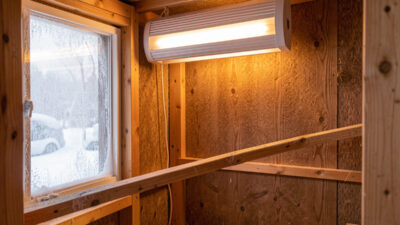 Insulated chicken coop interior with a wall-mounted radiant panel heater in winter