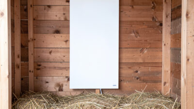 Flat radiant panel heater mounted on a chicken coop wall
