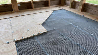 Coop floor being lined with half-inch hardware cloth with overlapping seams screwed down