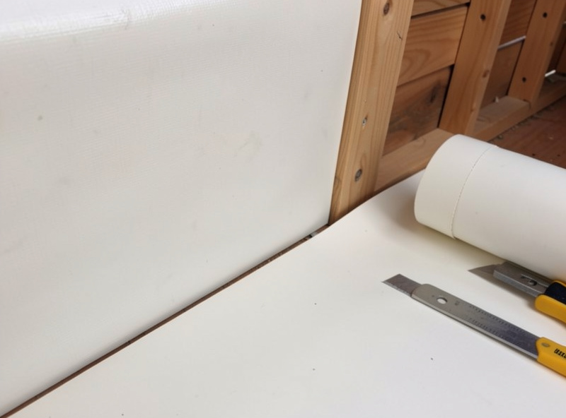 Sheet vinyl coved up a coop wall with no seam at the floor joint, roll of vinyl and utility knife nearby